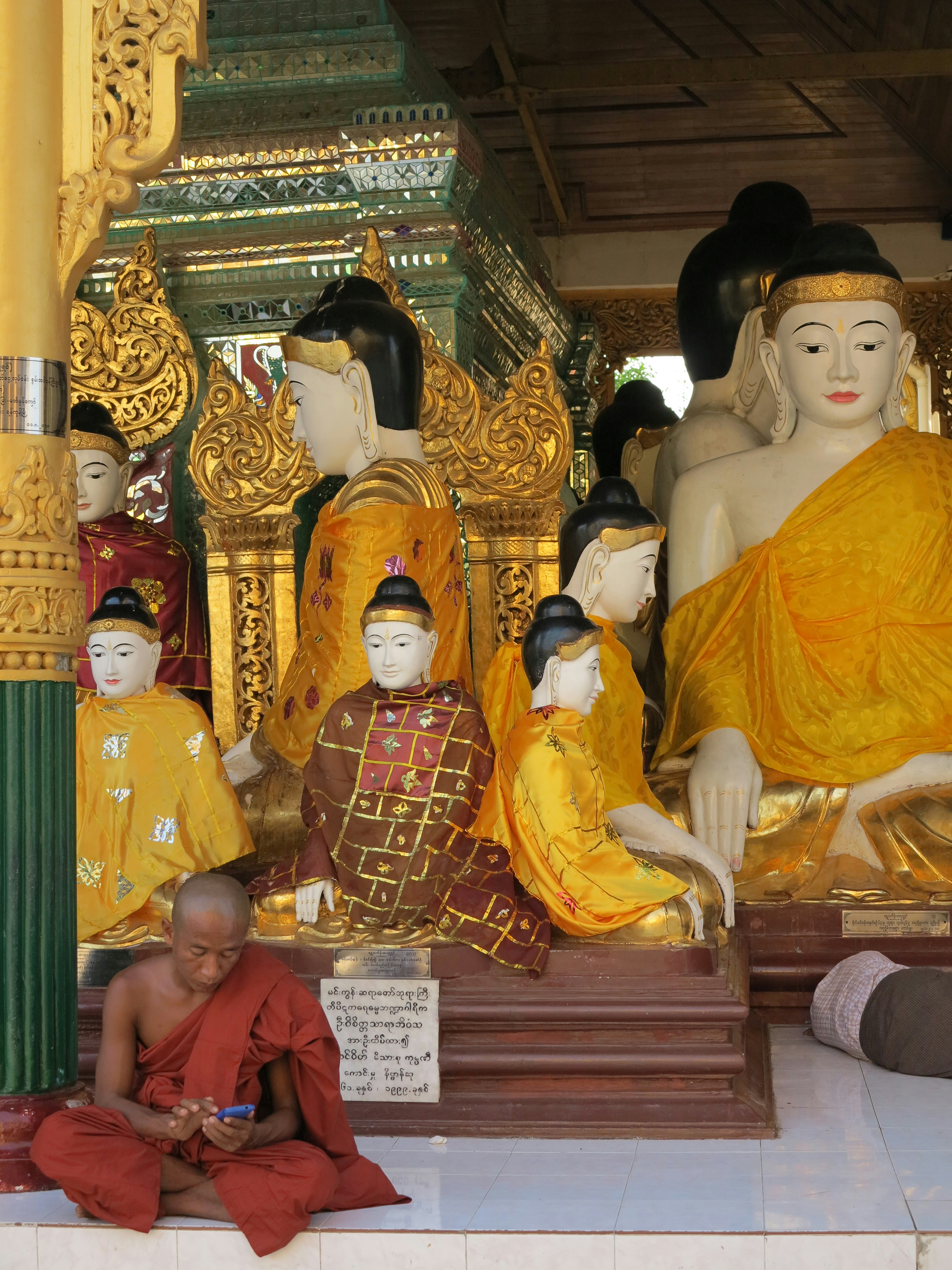 Un hombre sentado frente a una estatua de Budas
