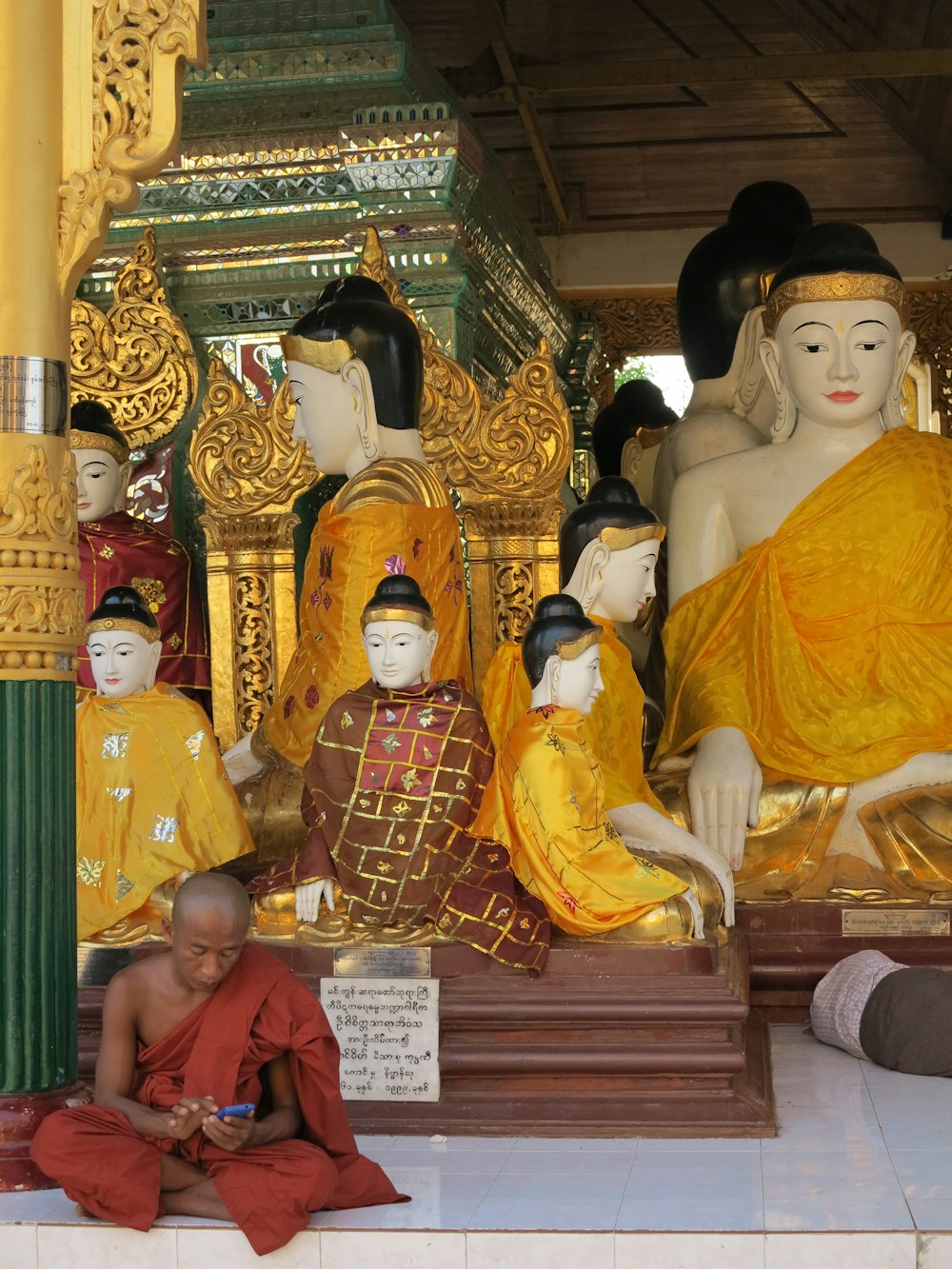 a man sitting in front of a statue of buddhas