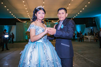 A softly lit photo of Adrianna and Lucas holding hands, surrounded by pastel decorations with powder blue accents.