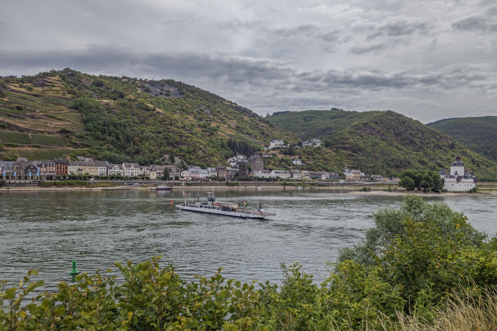 a boat traveling down a river next to a lush green hillside