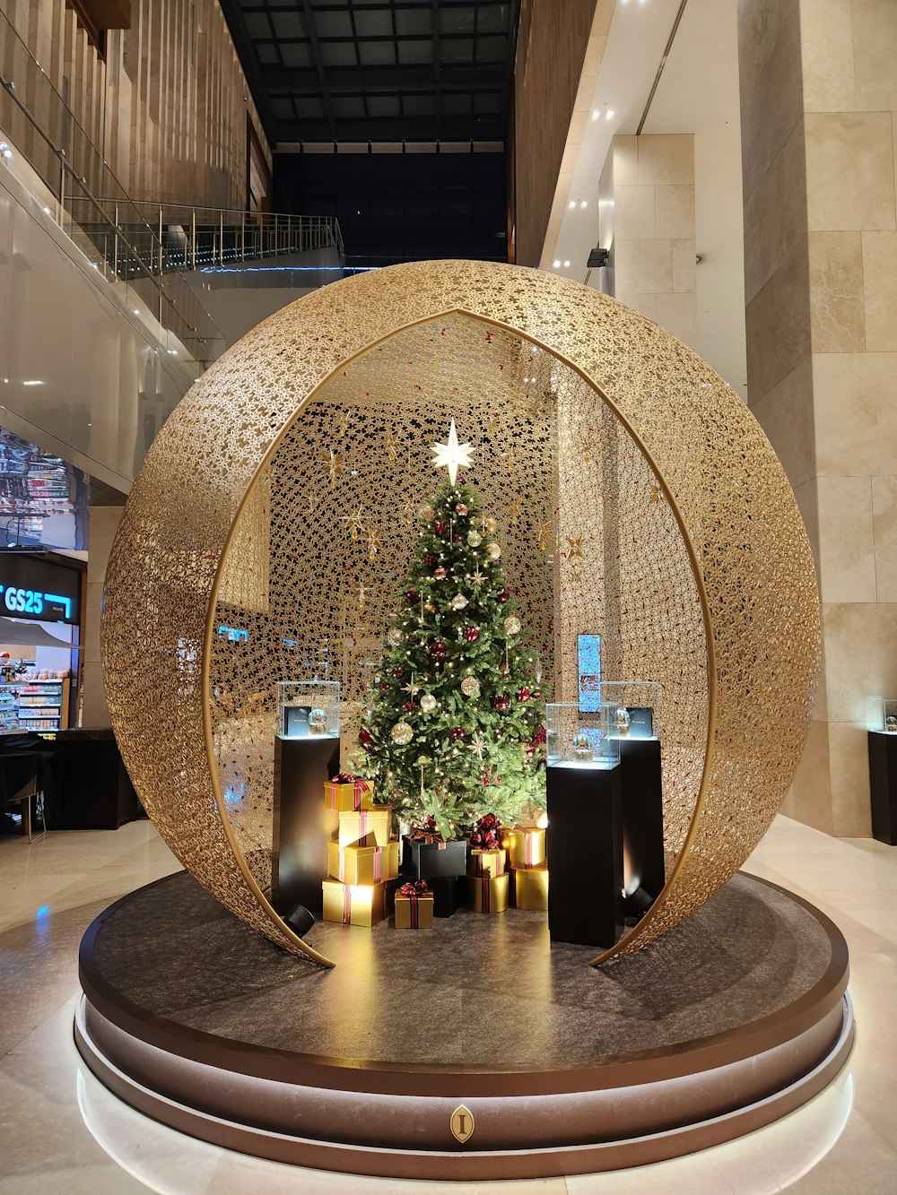 a christmas tree inside of a sphere in a lobby