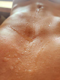 Close-up of a hand clutching a water bottle, beads of sweat glistening under soft natural light.