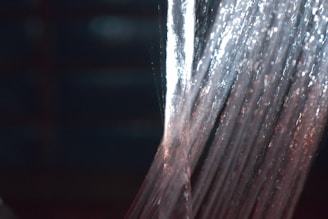 Water streams downwards in a continuous flow, illuminated by lights that create a shimmering effect. The texture and movement of the water are captured with a sense of fluidity and energy.