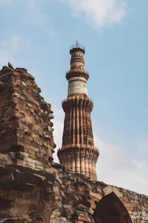 A scenic view of Qutub Minar's detailed architecture with a faded manuscript in the foreground.