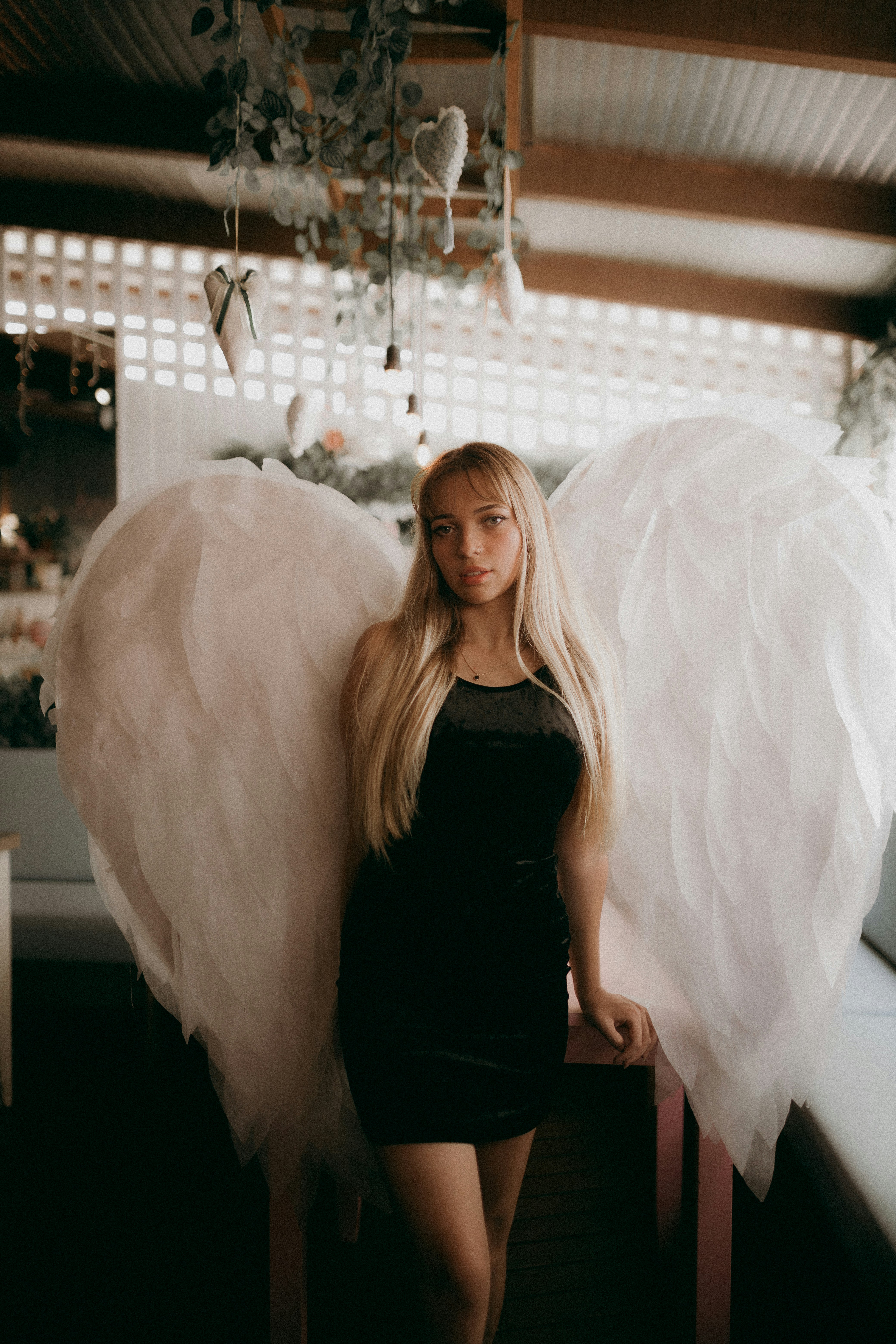 a woman in a black dress holding two white angel wings