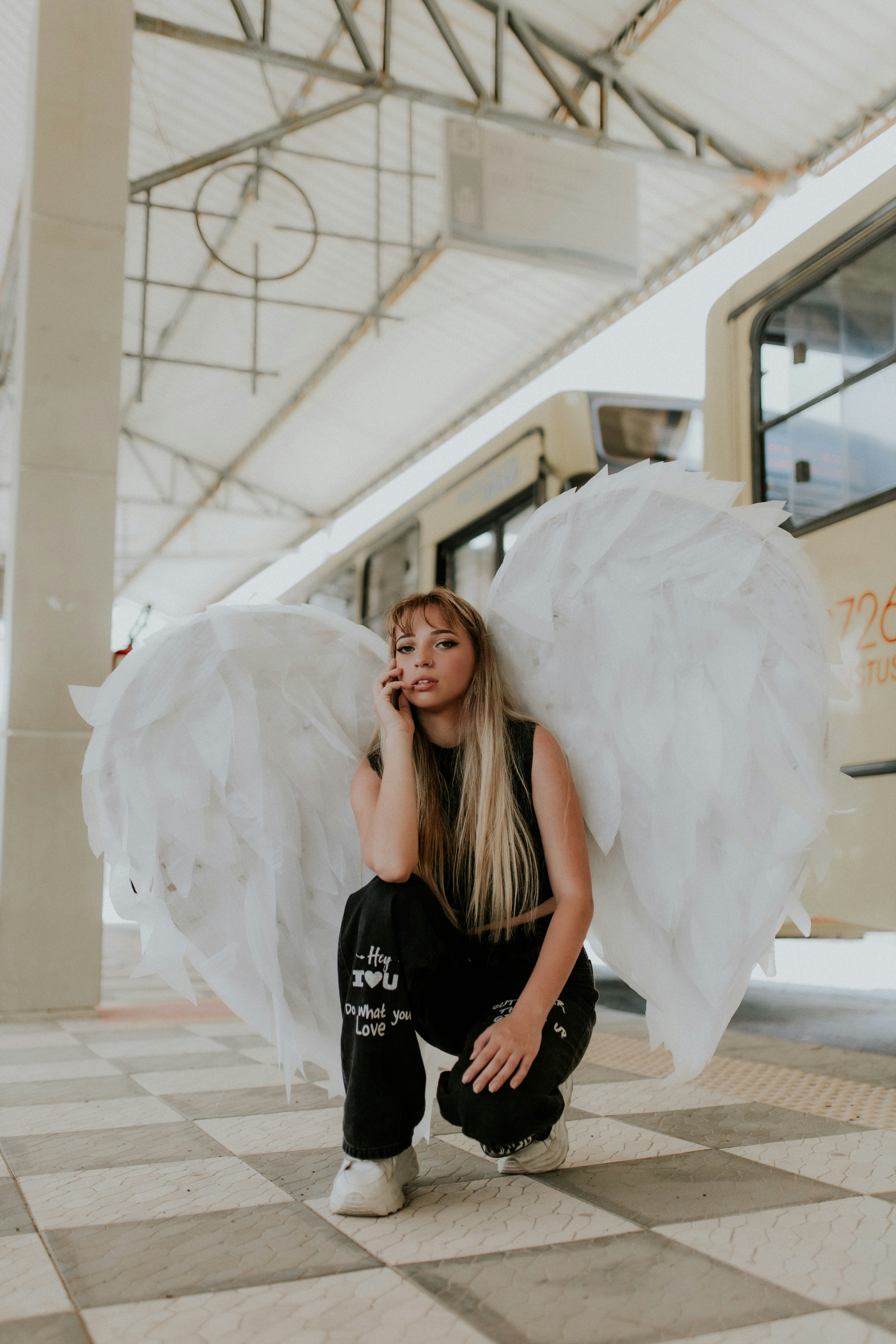 a woman sitting on a checkered floor holding a white angel wings