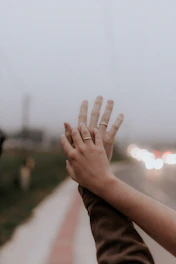 Two hands holding intertwined rings against a backdrop of starry night sky.