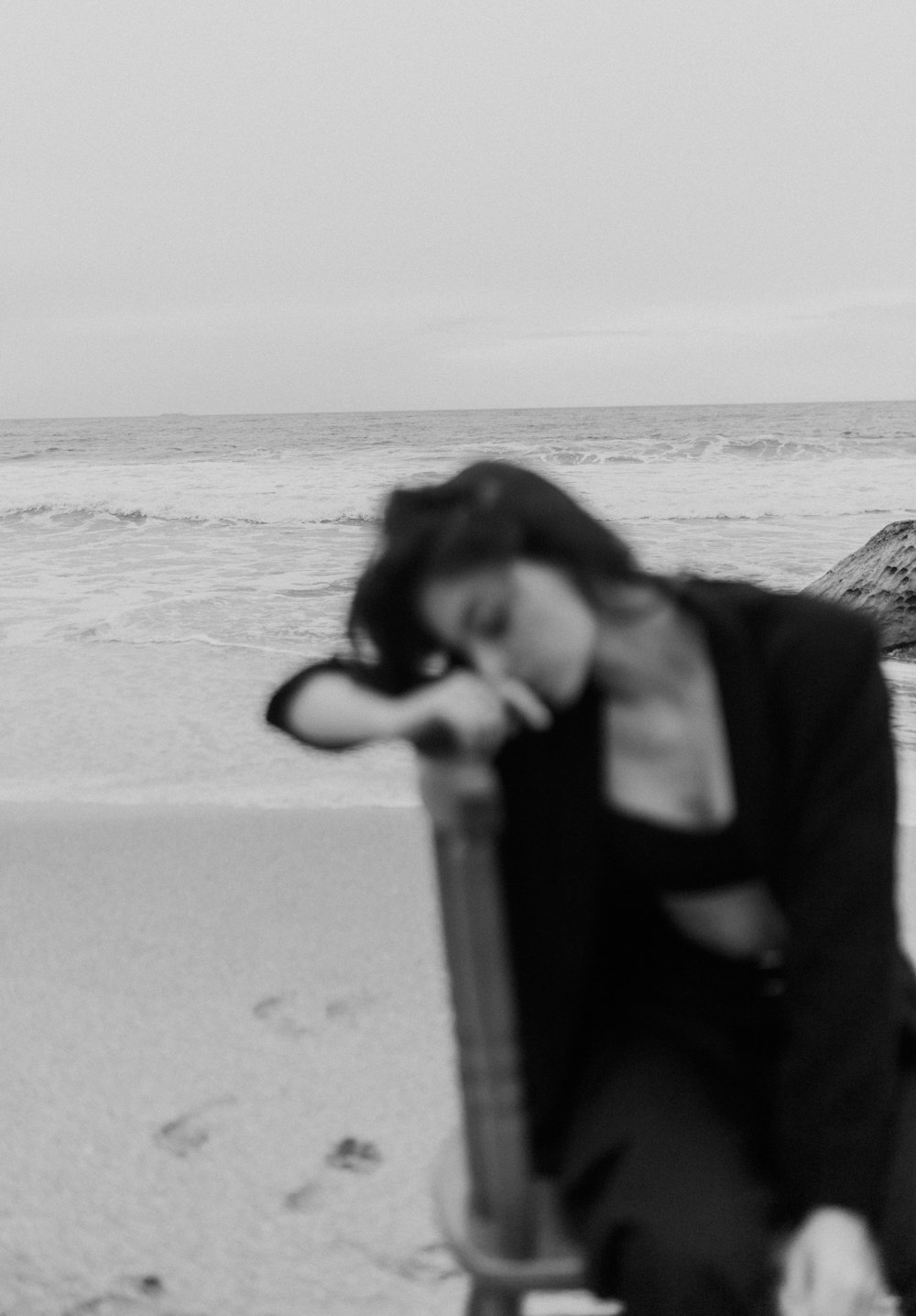 a woman sitting on a bench on the beach