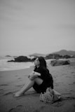 a woman sitting on a beach next to the ocean