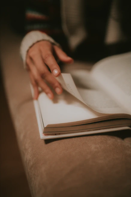 A close-up of hands gently turning the pages of a well-loved book