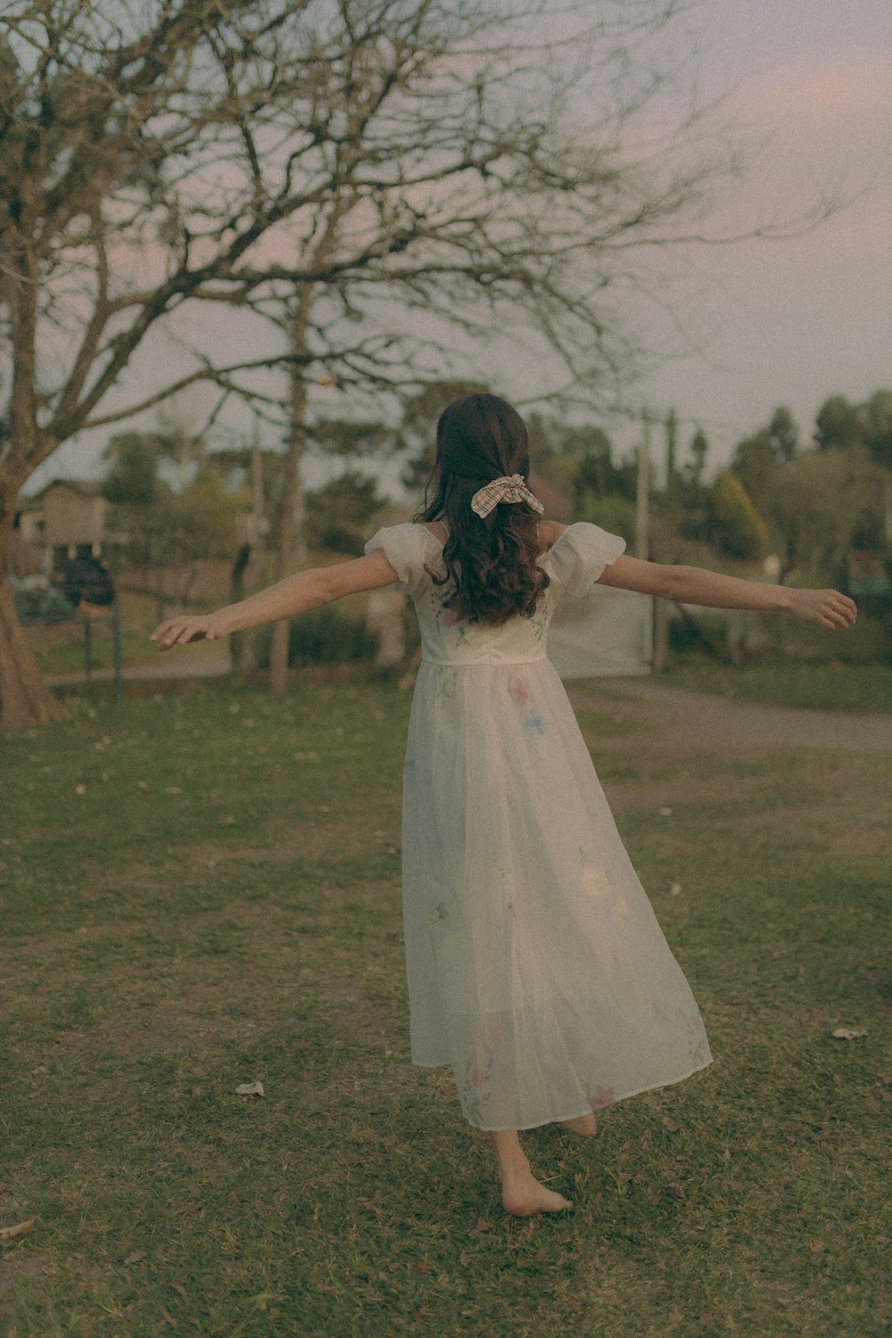 a young girl in a white dress standing in a field