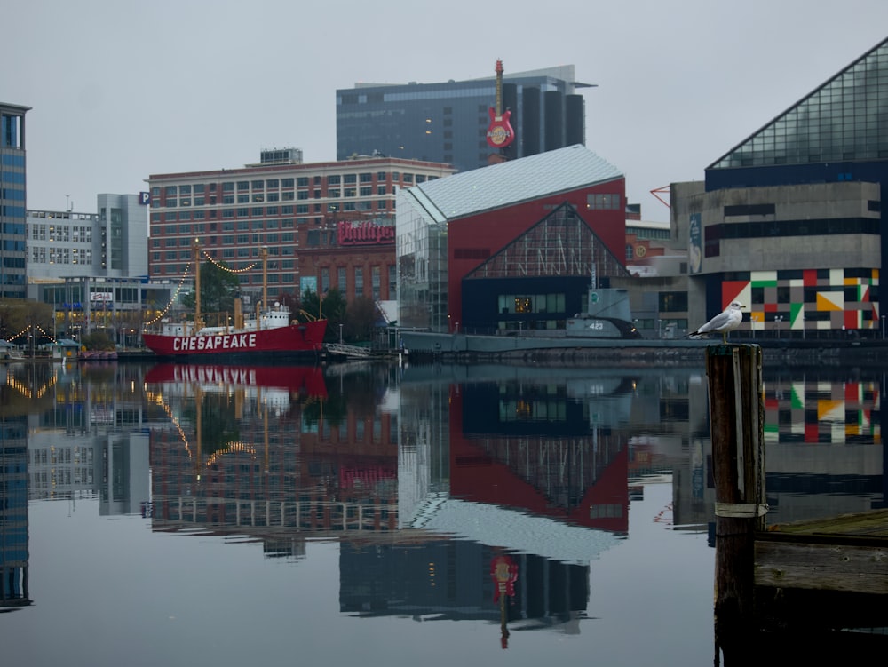 a red boat is in the water near some buildings