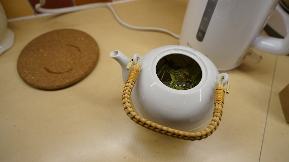 una tetera blanca con una planta verde en su interior