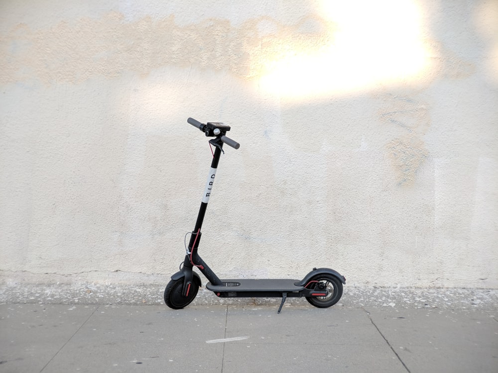 a scooter parked on a sidewalk next to a wall