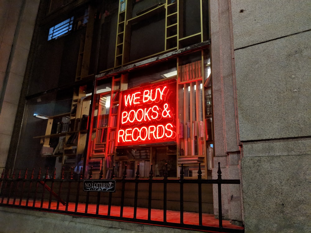 um letreiro de néon vermelho que diz que compramos livros e discos