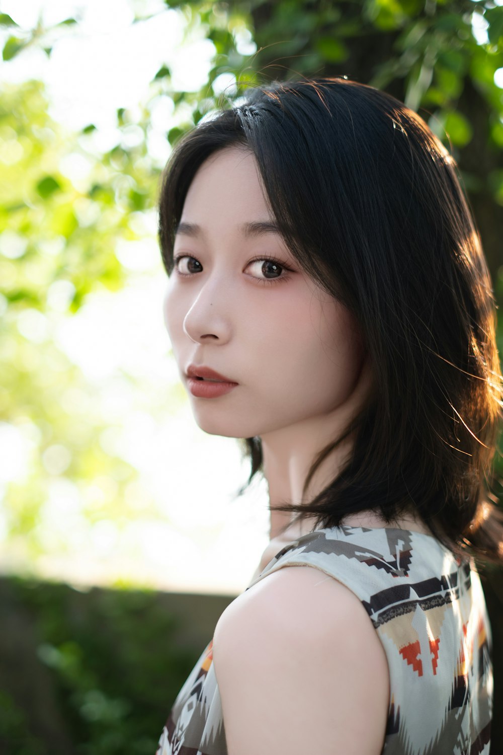 a woman with black hair standing in front of a tree