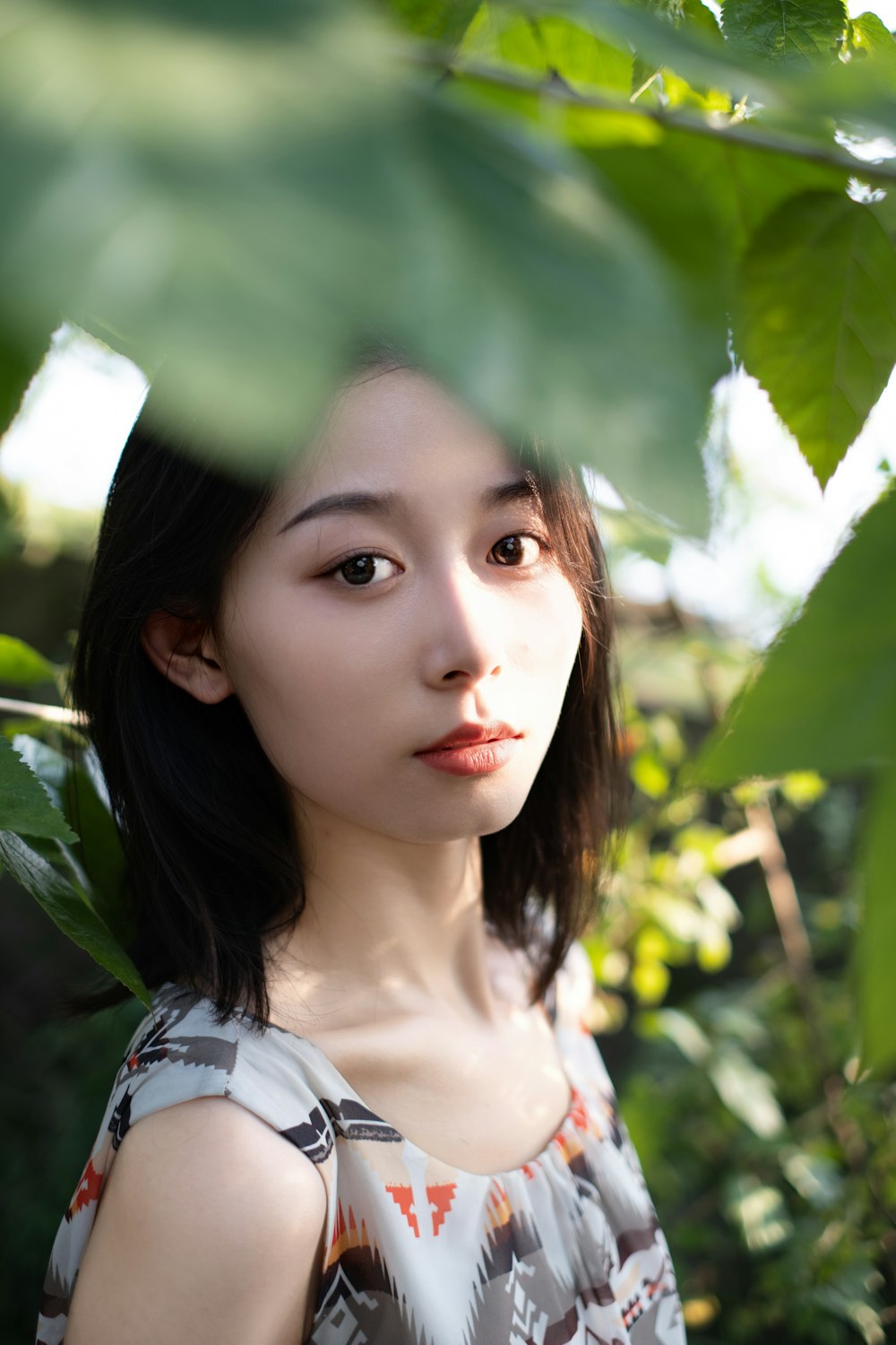 a woman standing under a leaf filled tree