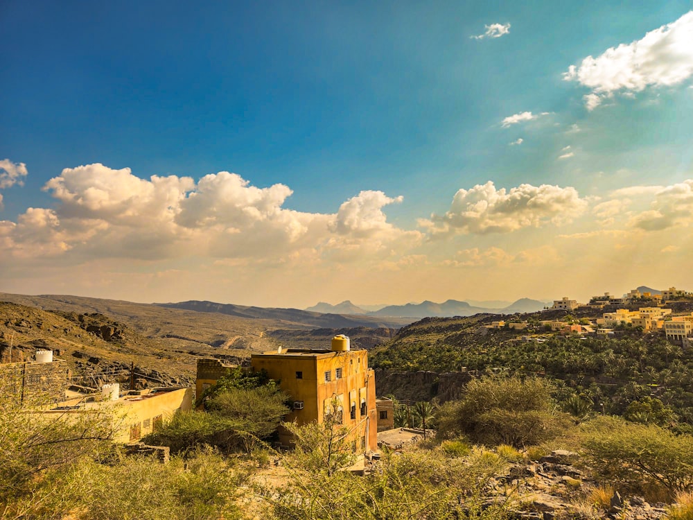 a yellow building sitting on top of a lush green hillside