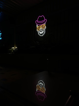 Dark neon skull with electric guitar glowing in purple and green hues on black background.