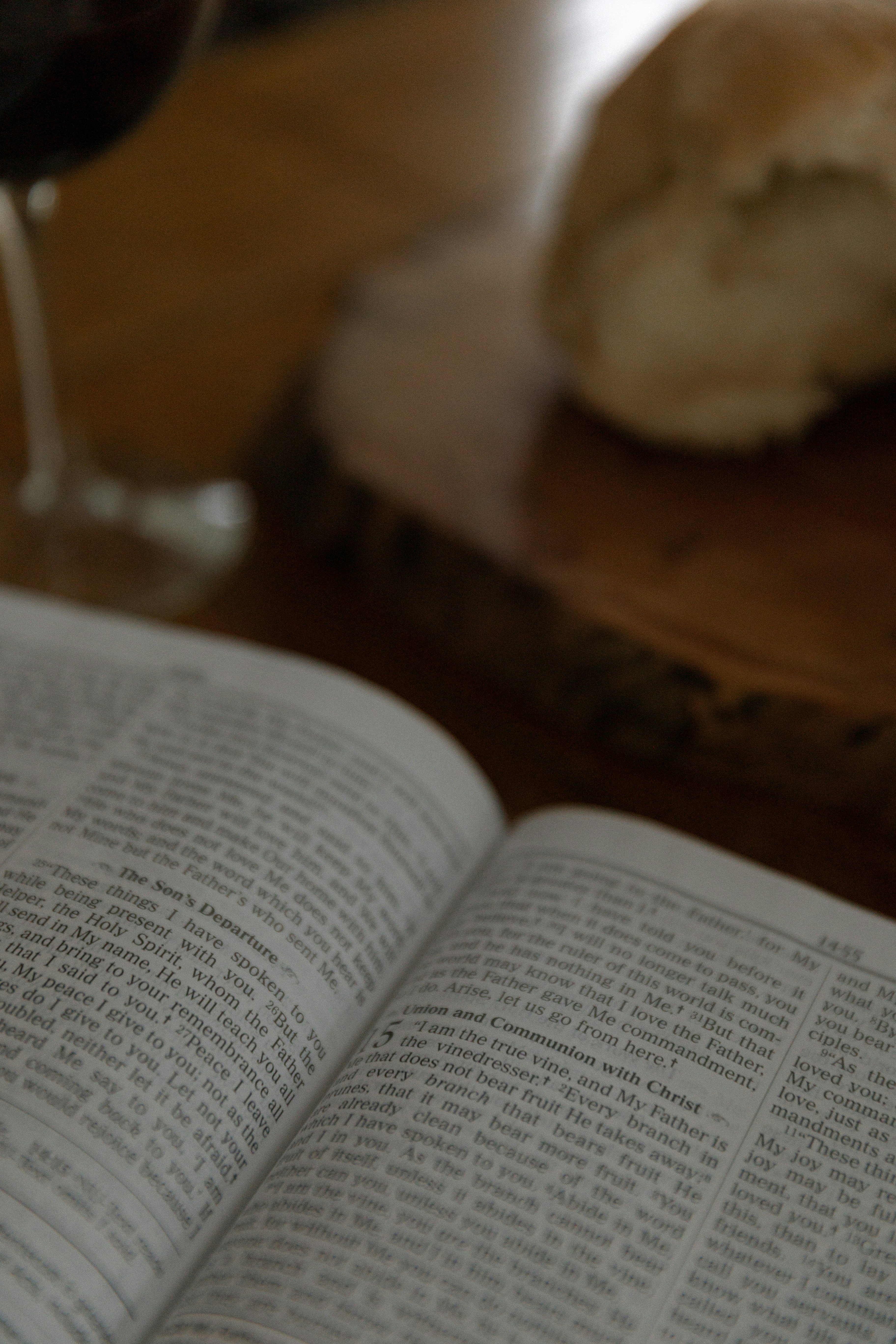 an open book sitting on top of a wooden table next to a glass of wine