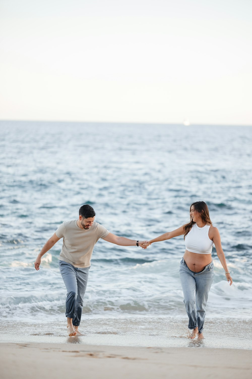 a man and a woman holding hands while walking on the beach