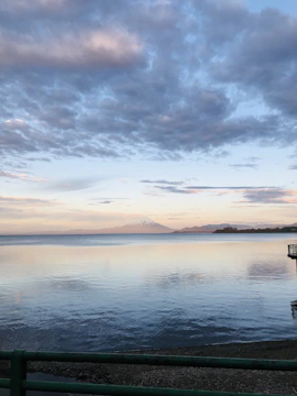 A serene mountain lake reflecting a pastel sunset sky.