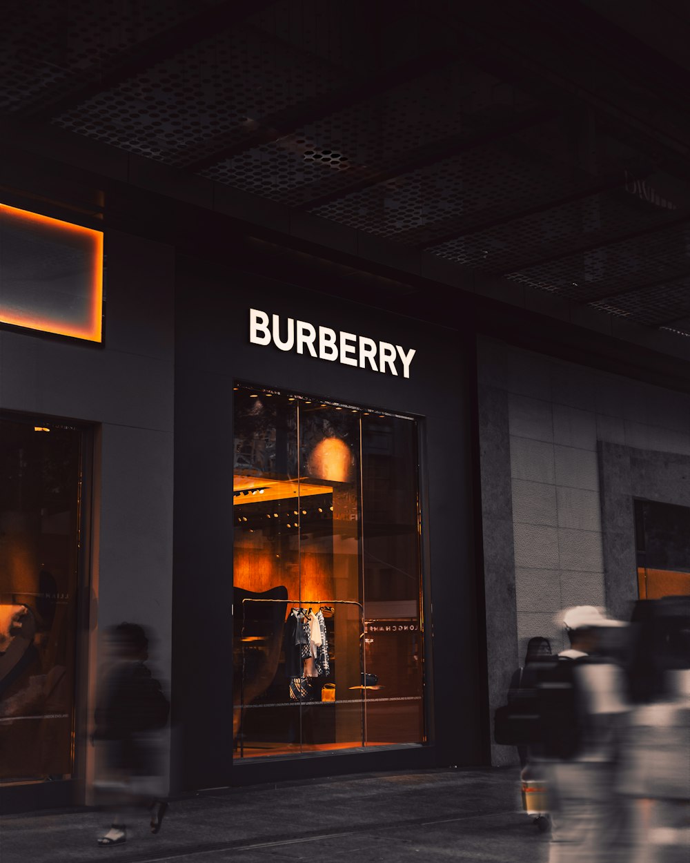 a blurry photo of people walking past a burbery store