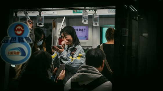 A smiling commuter using the CairoCommute app on their phone while waiting at a busy Cairo bus stop.