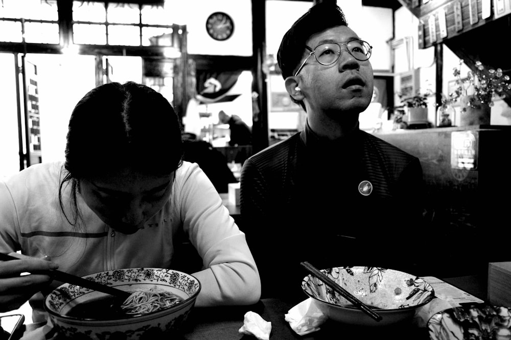 a couple of people sitting at a table with plates of food