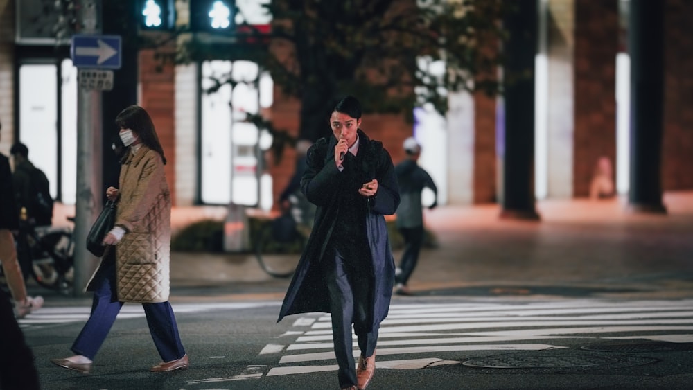 a man walking across a street while talking on a cell phone