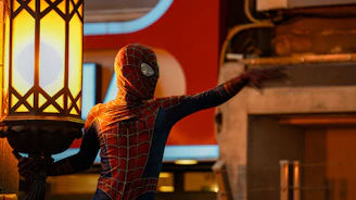 Close-up of a sleek black and red Spider-Man mask with glowing eye lenses.