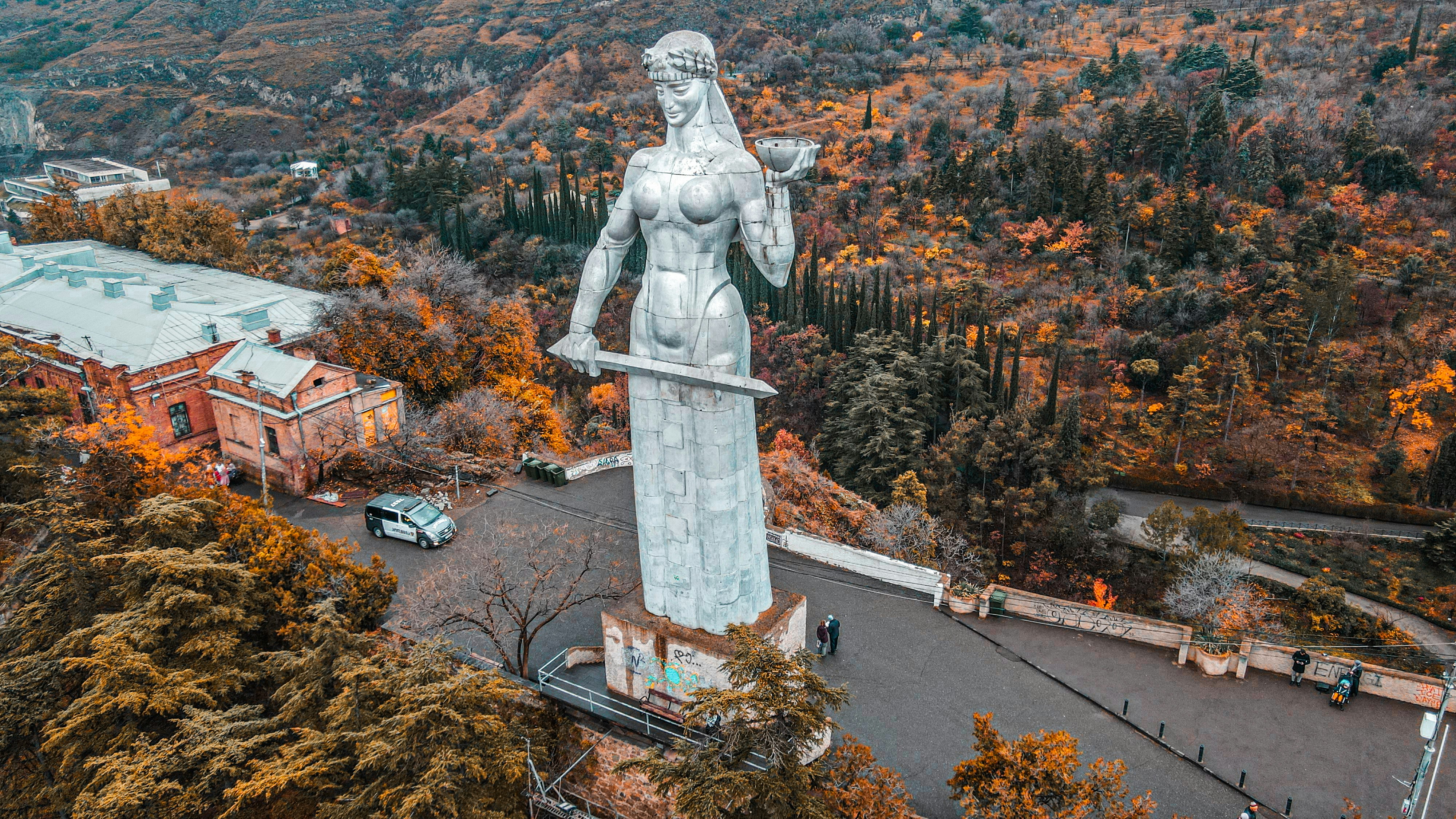 an aerial view of a statue of a woman surrounded by trees