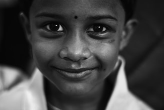 A black and white portrait of a young child smiling softly in natural light