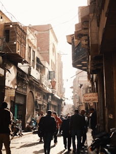 a group of people walking down a street next to tall buildings