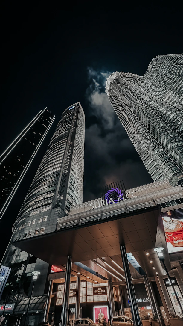 A sleek, dark-toned image of a luxury high-rise apartment overlooking the KLCC skyline at dusk.