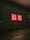 A dark street with a large glass window featuring a bright red and white UNIQLO logo, illuminated against the dark surroundings. The arrow painted on the pavement in the foreground points towards the glass wall.