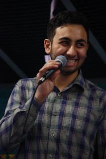 A smiling singer holding a microphone in a rustic bluegrass setting.