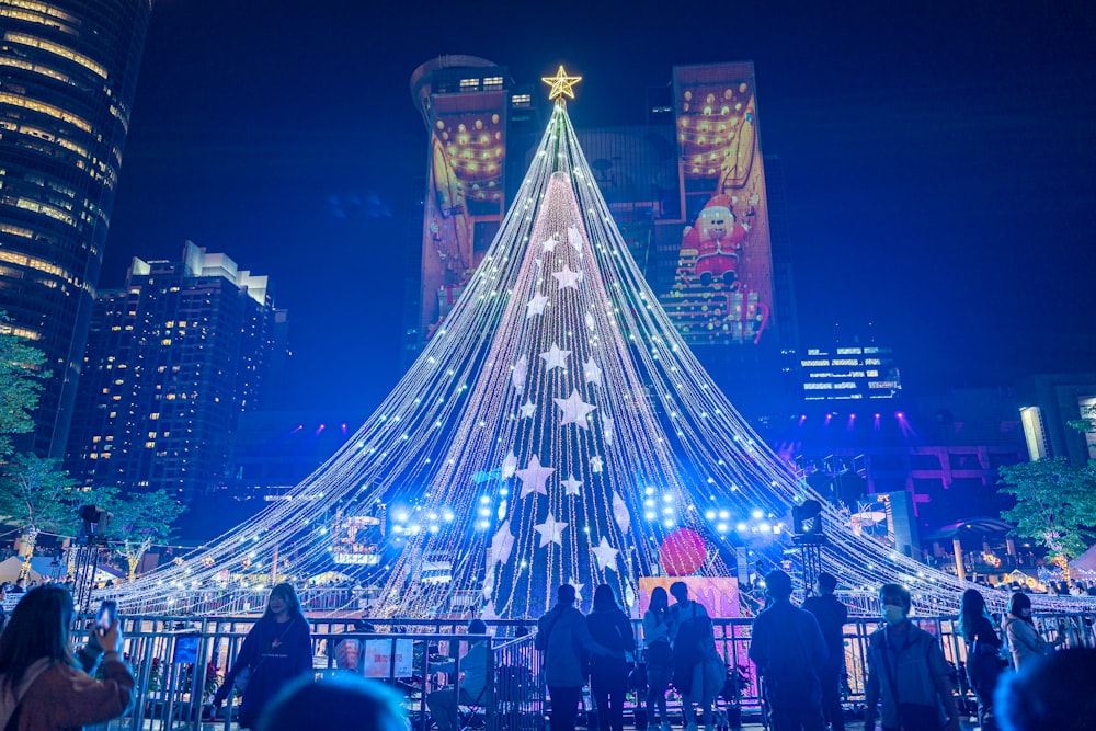 Un grande albero di Natale è illuminato nel mezzo di una città