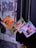 Three spiral-bound booklets with colorful covers are hanging from strings against a textured wall. Each cover features different people and text in a language that appears to be Korean.