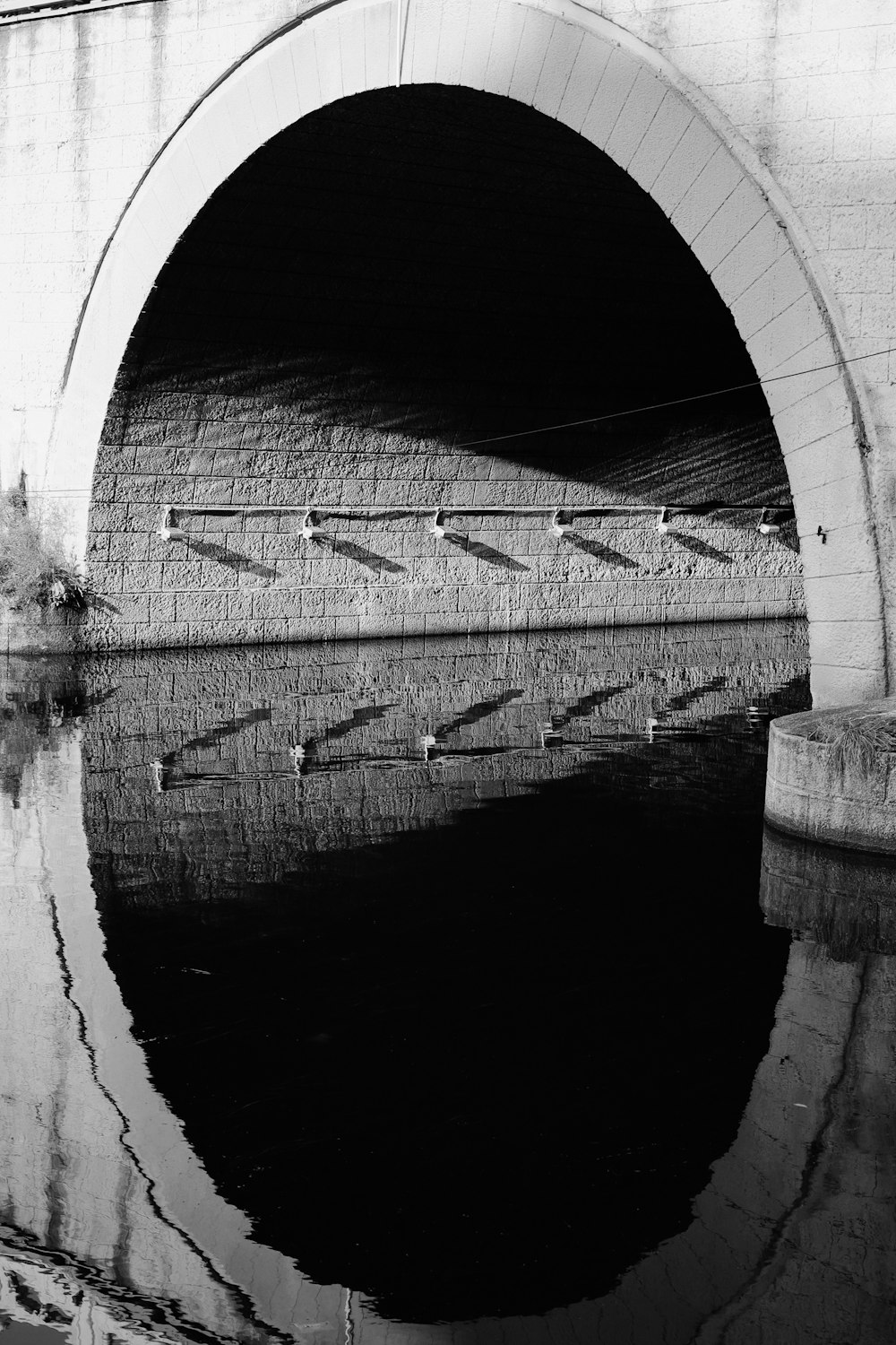 a black and white photo of a bridge over water