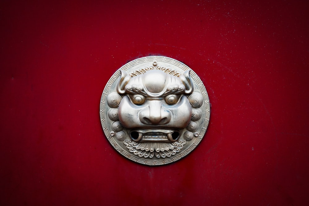 a metal lion head on a red wall