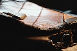Close-up of a leather purse with detailed stitching on a neutral background.