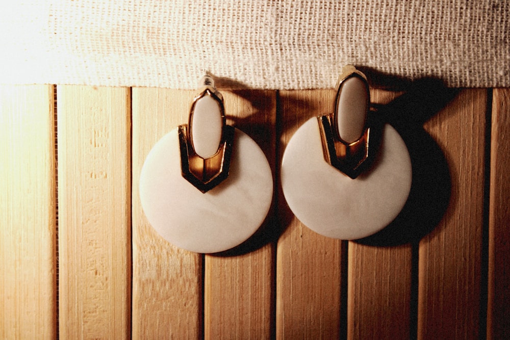 a pair of white and gold earrings hanging on a wall