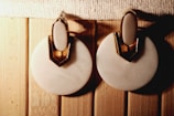 Pair of shiny stainless steel earrings resting on a marble surface.