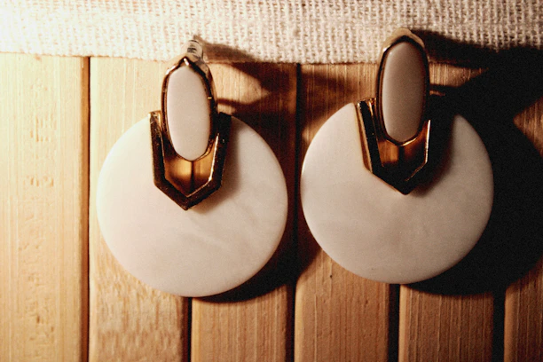 Elegant flat lay of Lustra earrings on a white marble surface with gold accents.
