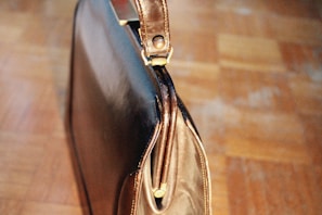 A sleek leather briefcase resting on a polished wooden desk next to a British newspaper.