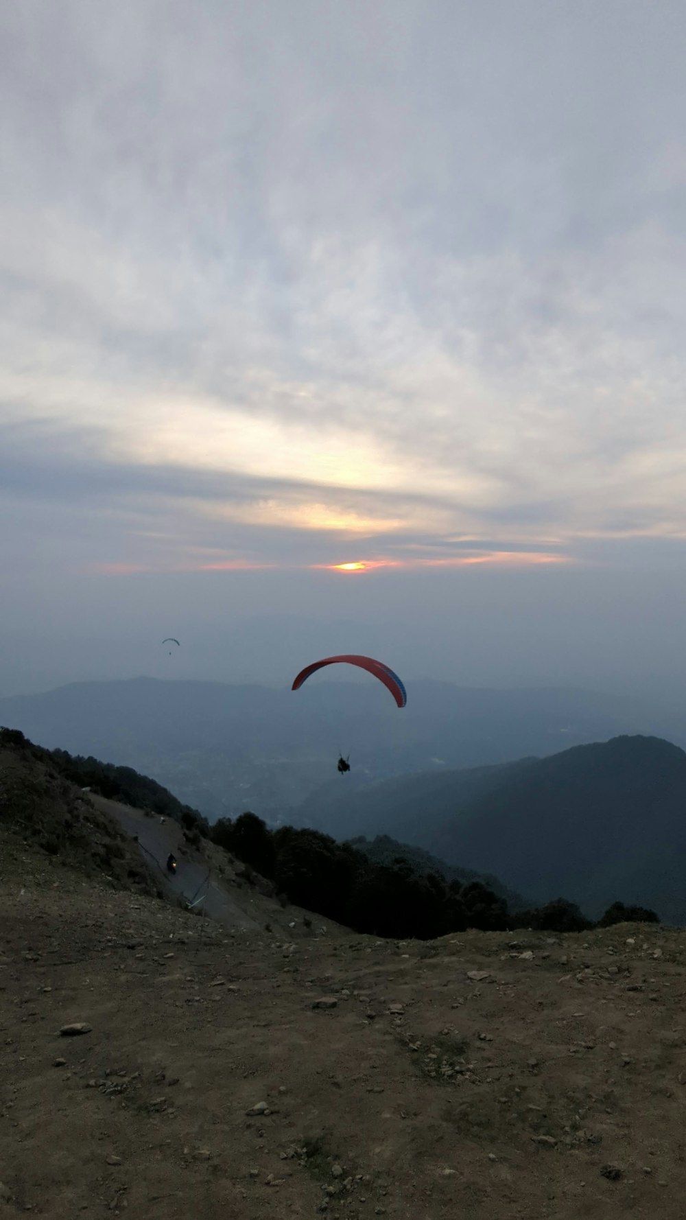 a paraglider flying over a mountain at sunset