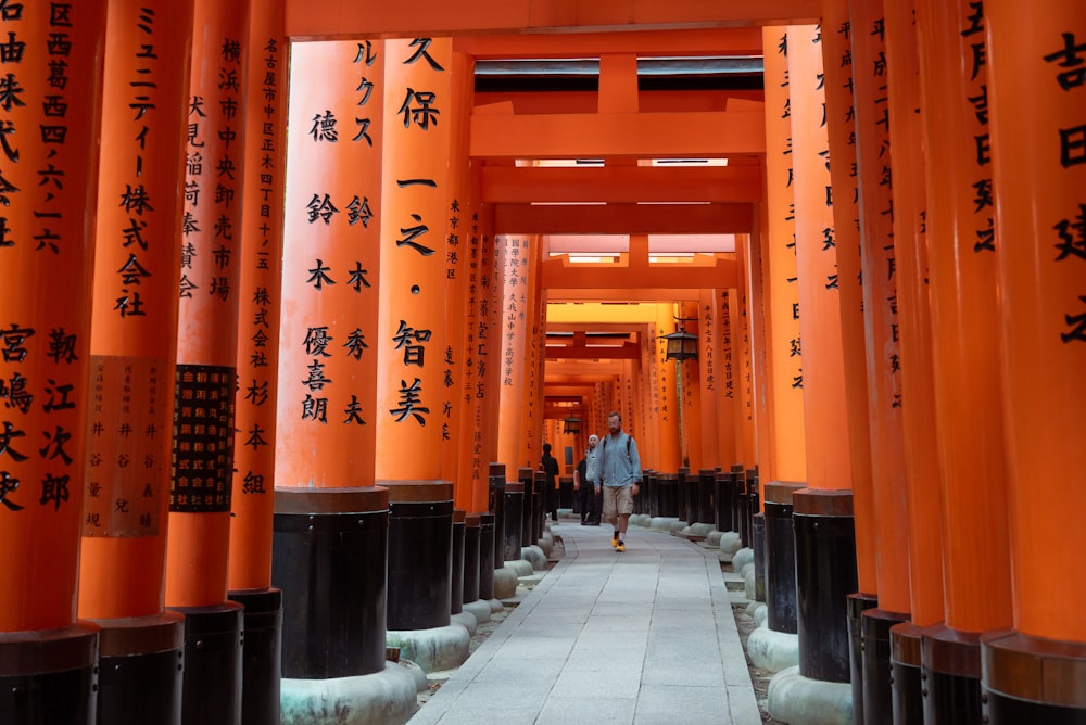 Ein Mann, der durch einen Tunnel aus orangefarbenen Tori tori tori tori tori tori tori