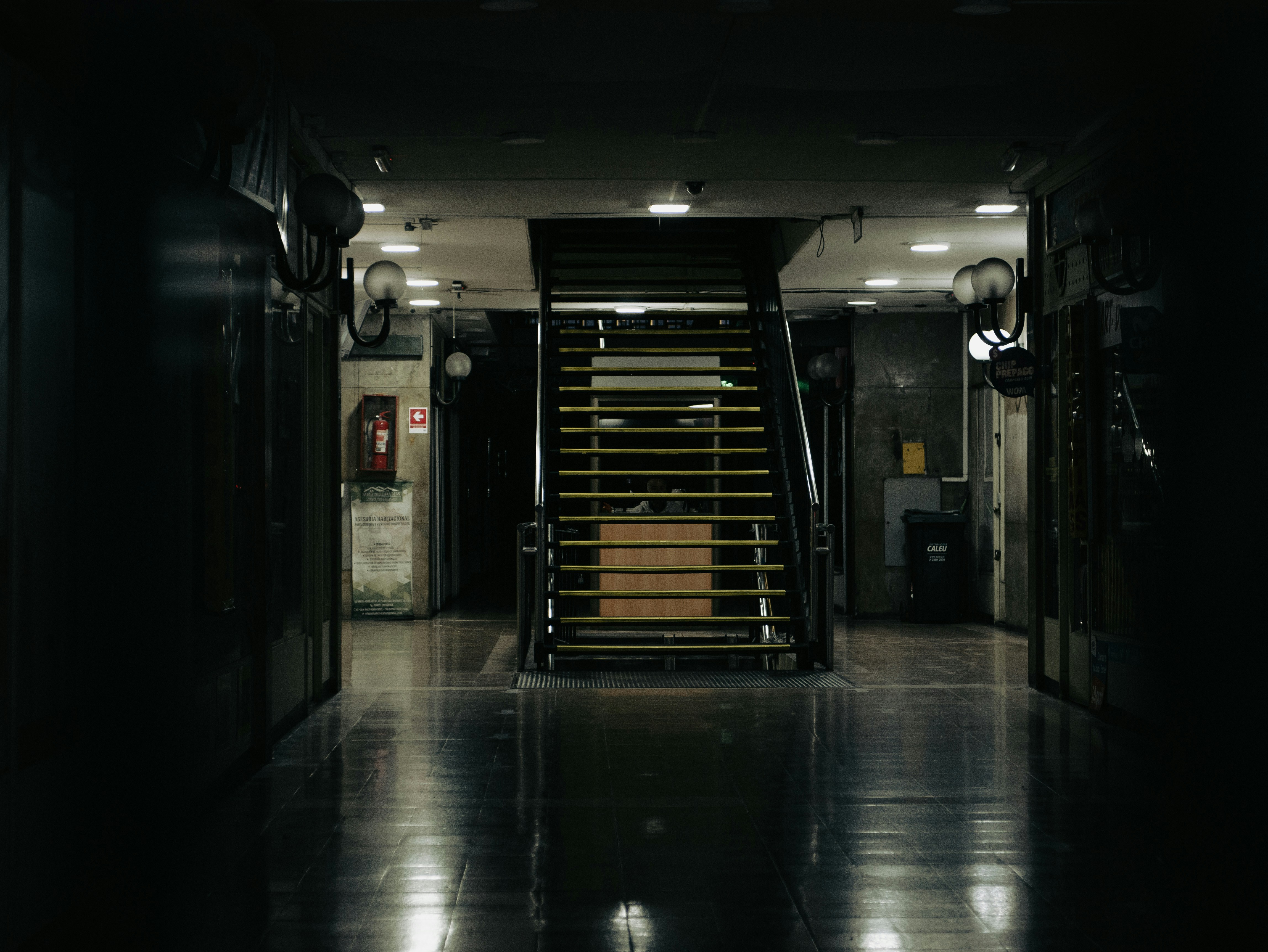 Dark hallway with stairs leading to a phone booth