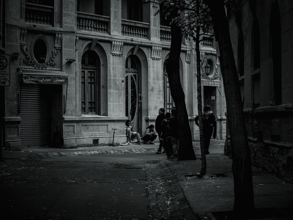a black and white photo of people sitting on a bench in front of a building